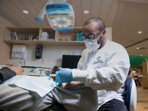 An Orthodontics student works on a patient whose face we can't see.